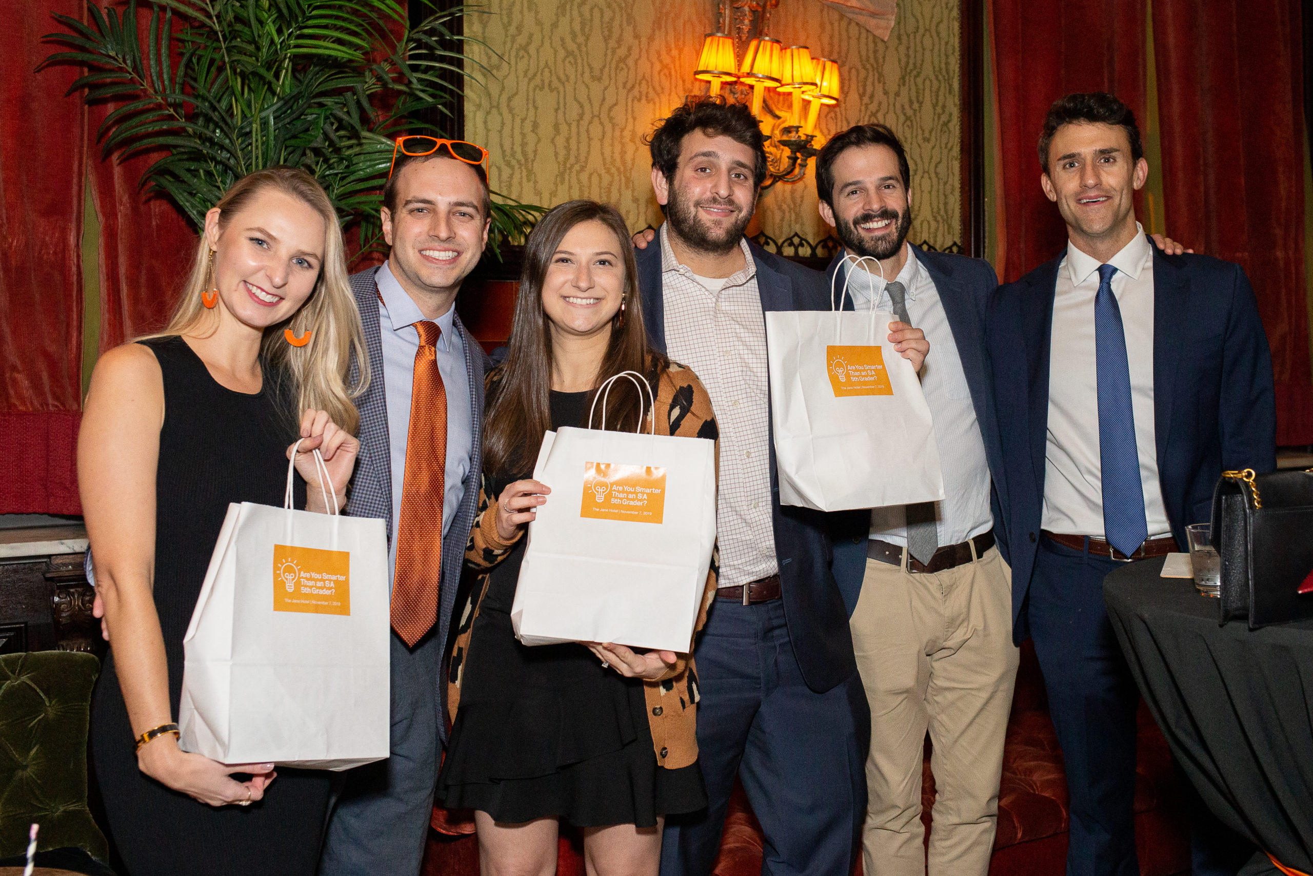 Child wearing glasses raises hand, smiling indoors.