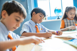 Three students at a table working on art projects